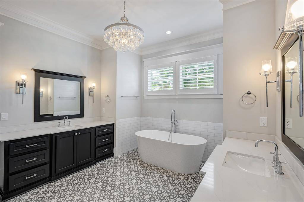 Spa-inspired primary bath offers a soaking tub, dual sinks, elegant lighting, and sleek modern fixtures and tile.