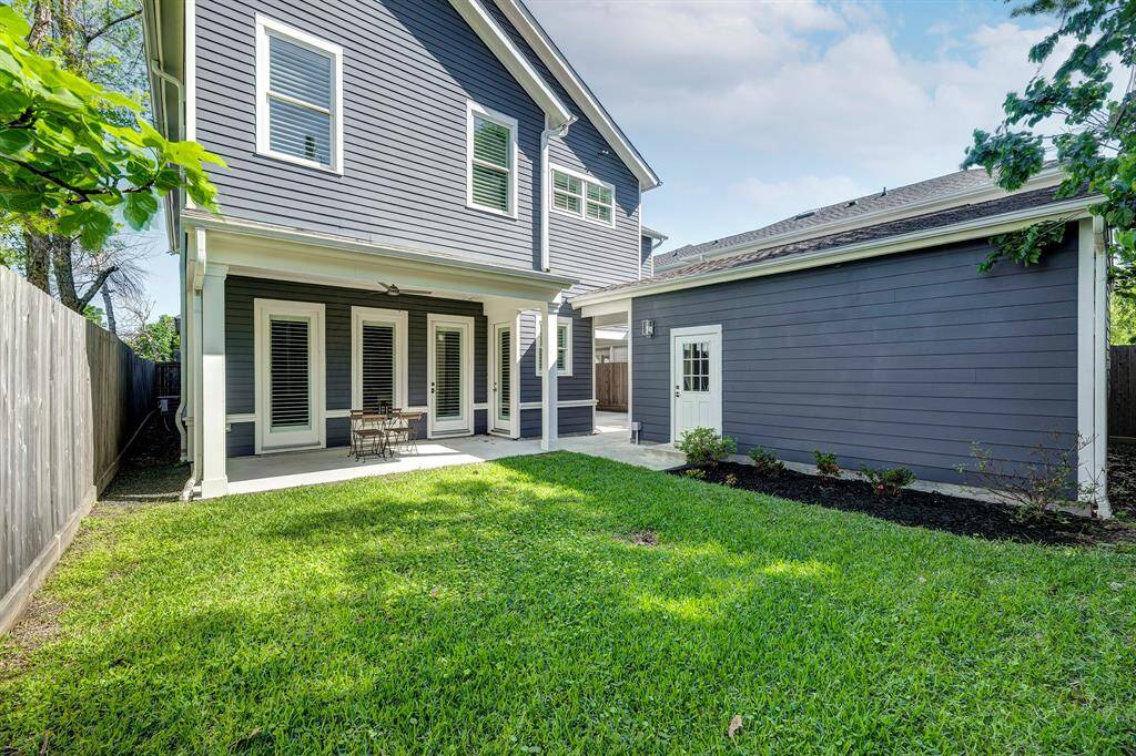Rear view of the home showcasing the green space, garage, and covered back porch.