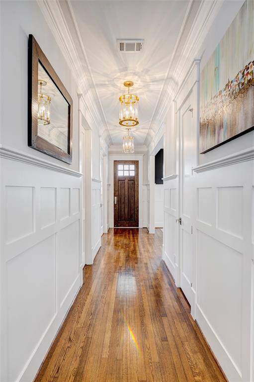 Elegant entryway featuring rich hardwood floors, contemporary light fixtures, and intricate wainscoting details.