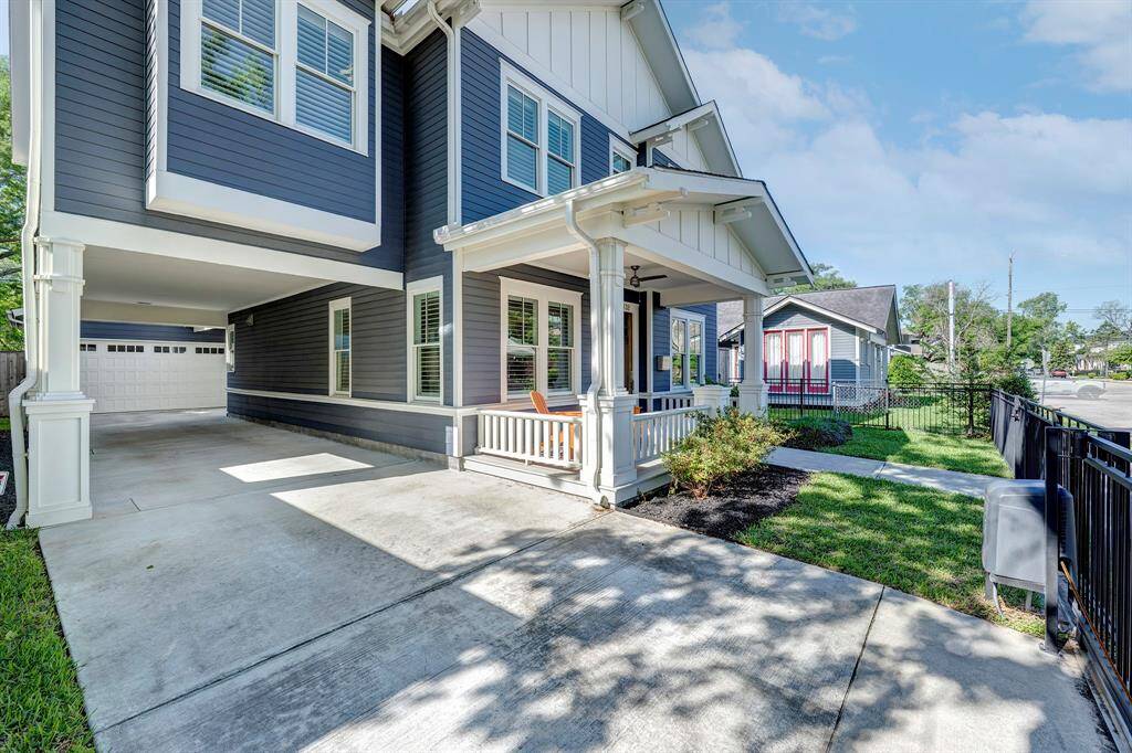 A different perspective of the home’s front, showcasing the front yard, extended driveway, driveway gate, and front porch.