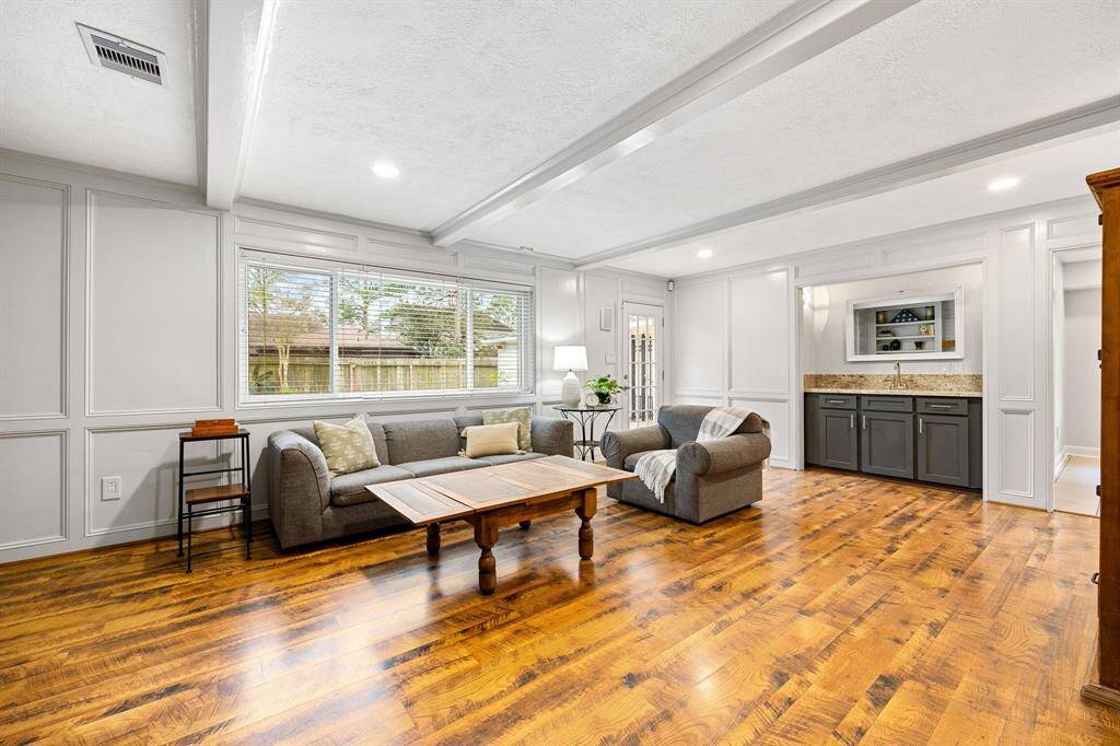 The family room is adorned with detailed moldings and ceiling beams along with a wet bar, giving this space charm and elegance.