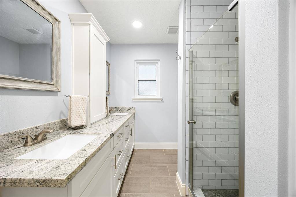 Double-sink vanity with gorgeous countertops with upgraded fixtures along with stand-alone shower.
