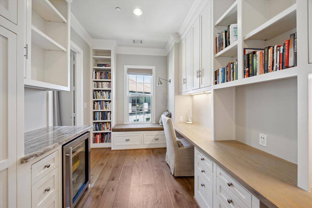 The secondary closet in the owner’s suite has been converted into a home office. There’s impressive storage for supplies and documents, along with a beverage fridge and coffee station to the right.