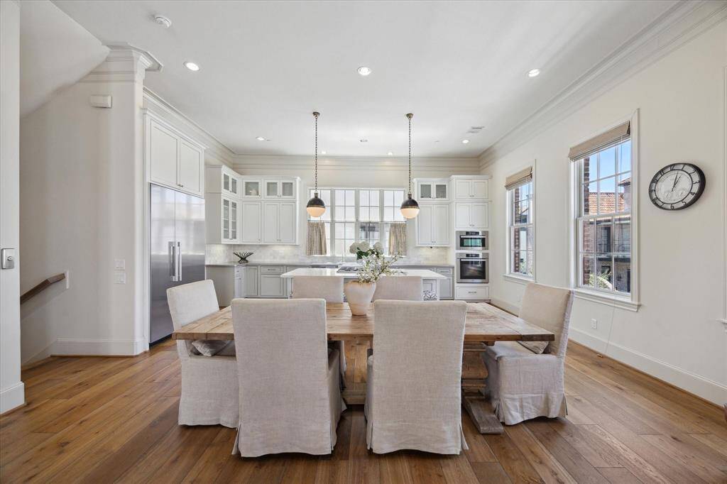 From the living room, enjoy the open flow into the dining and kitchen areas. Dramatic ceilings and an abundance of natural light enhance the space. Double doors open onto a second-floor balcony.