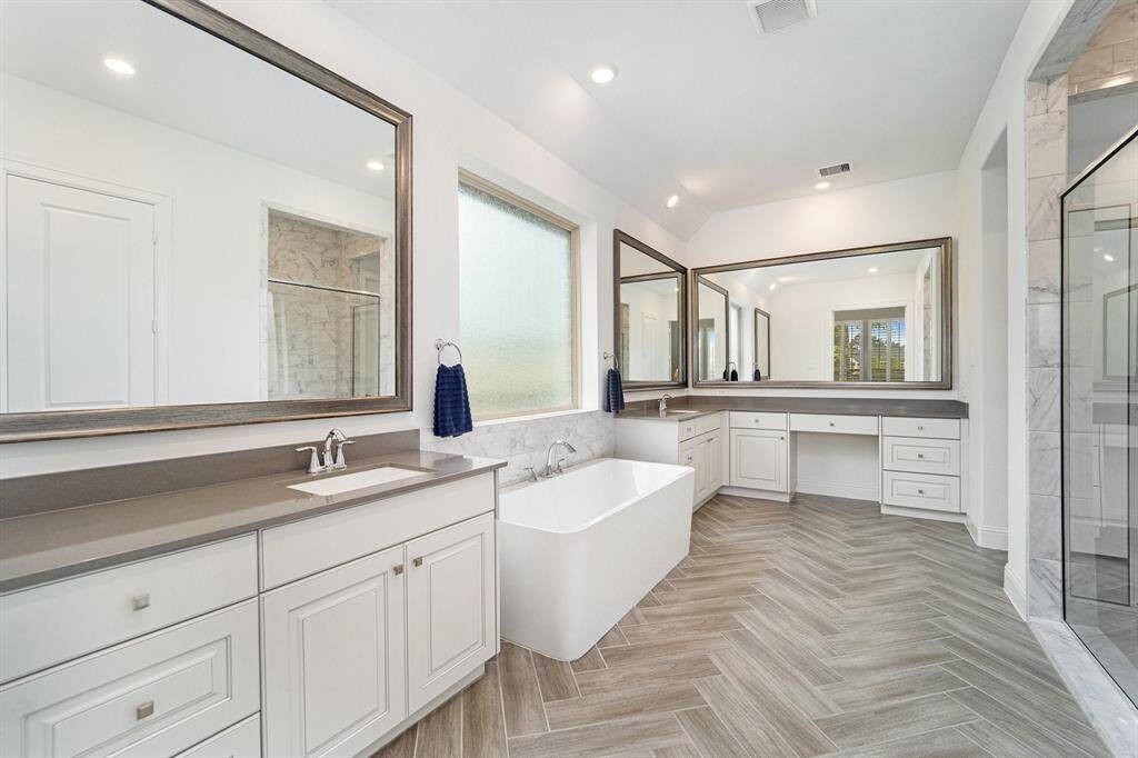 Lavish en suite showcases dual vanities, ample countertop space, and a soaking tub.