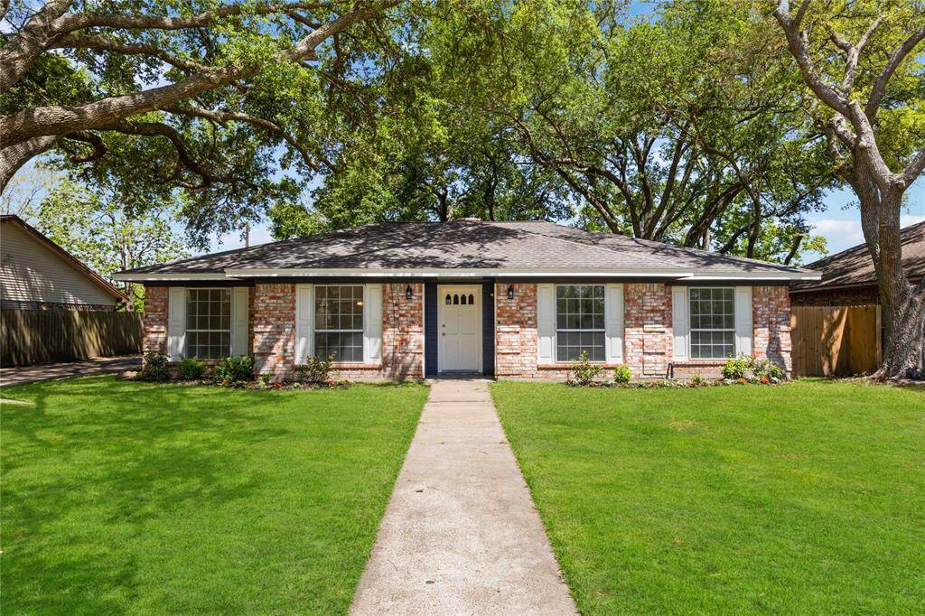 Charming single-story brick home with a welcoming facade, large front windows, and a well-maintained lawn. Mature trees provide shade and add to the curb appeal.