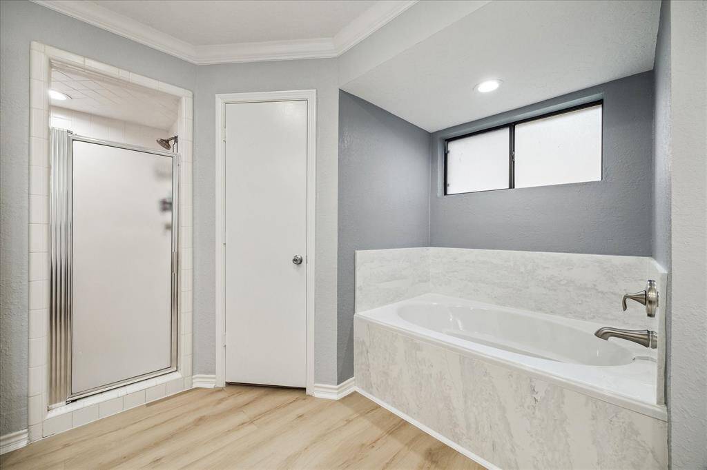 This is the other side of the of the primary ensuite bath showcasing the separate shower, soaking tub and one of the two closets.
