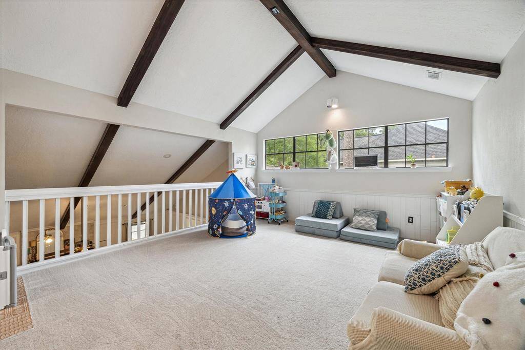 Upstairs is the well-lit loft-style game room.  Notice the recent wood beams highlighting the vaulted ceiling and  mimicking the ceiling aesthetic of the family room below. The upstairs has all recent carpet *per seller.