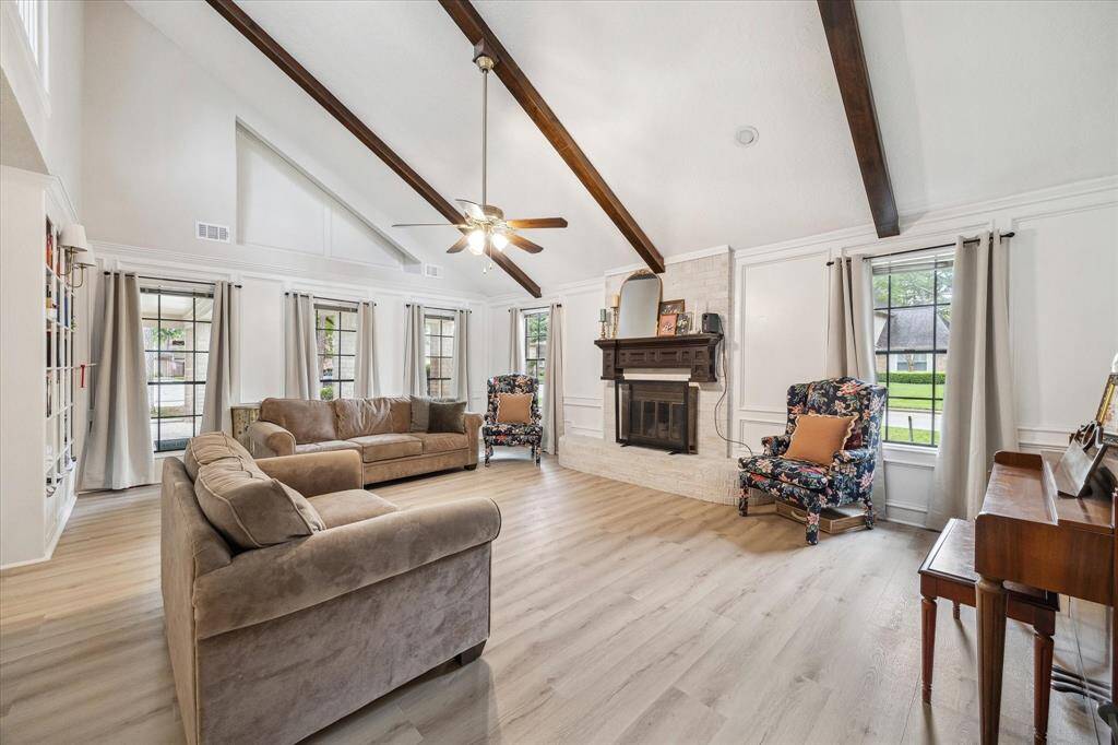 The massive family room is accented by a vaulted ceiling, neutral LVP flooring, built in bookcase, and a gas fireplace with decorative mantle. Natural light floods this room from five tall windows. Homeowners enjoy access directly into the 3-car garage from a door in the near right corner.