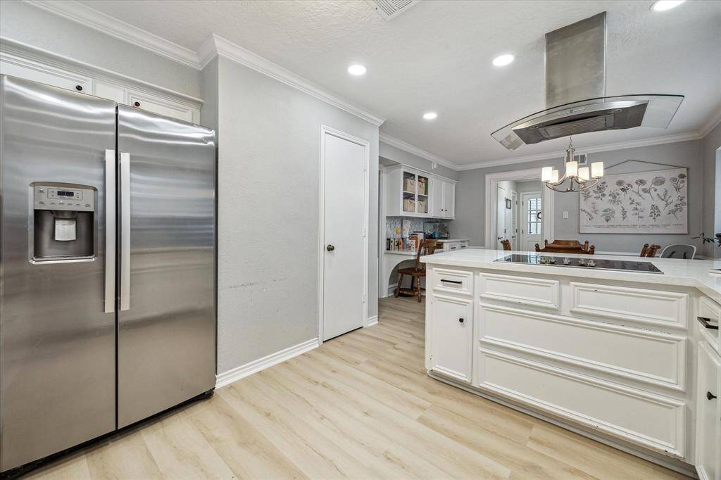 The adjoining breakfast room features a built-in desk and upper display cabinets.  The door in the background of this photo opens to a half bath, separate large utility room and exit door that opens to the backyard patio.