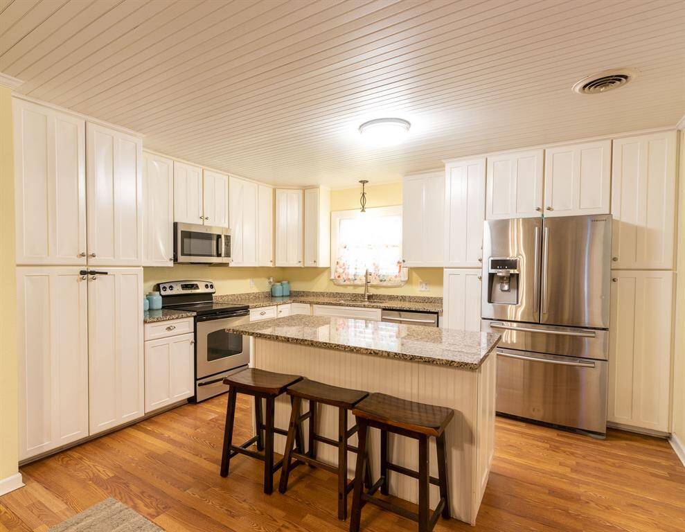 Lots of cabinetry. Kitchen island with breakfast bar in the foreground.