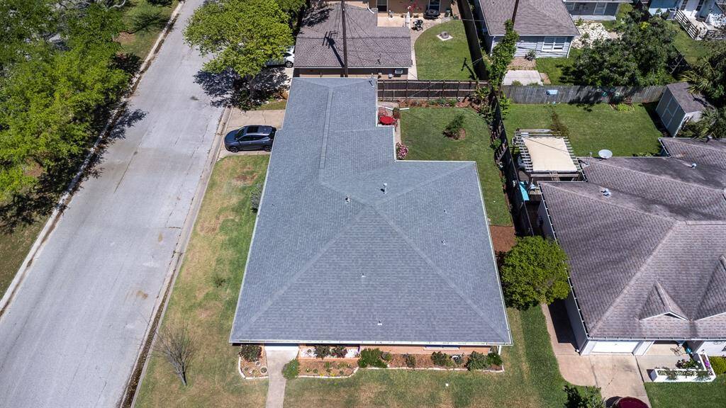 Aerial view showing the placement of the house on the lot with the fenced backyard, the driveway. Marine Drive on the left.