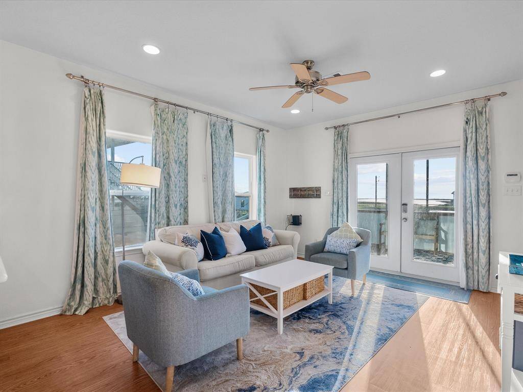 The space includes a comfortable sofa, armchair, and stylish decor, with large windows and glass doors leading to the outdoor area.
