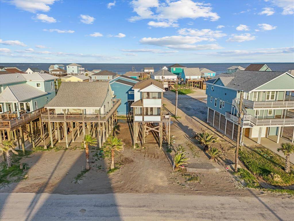This coastal property features elevated beach houses with ocean views, sandy surroundings, and nearby palm trees, ideal for seaside living.