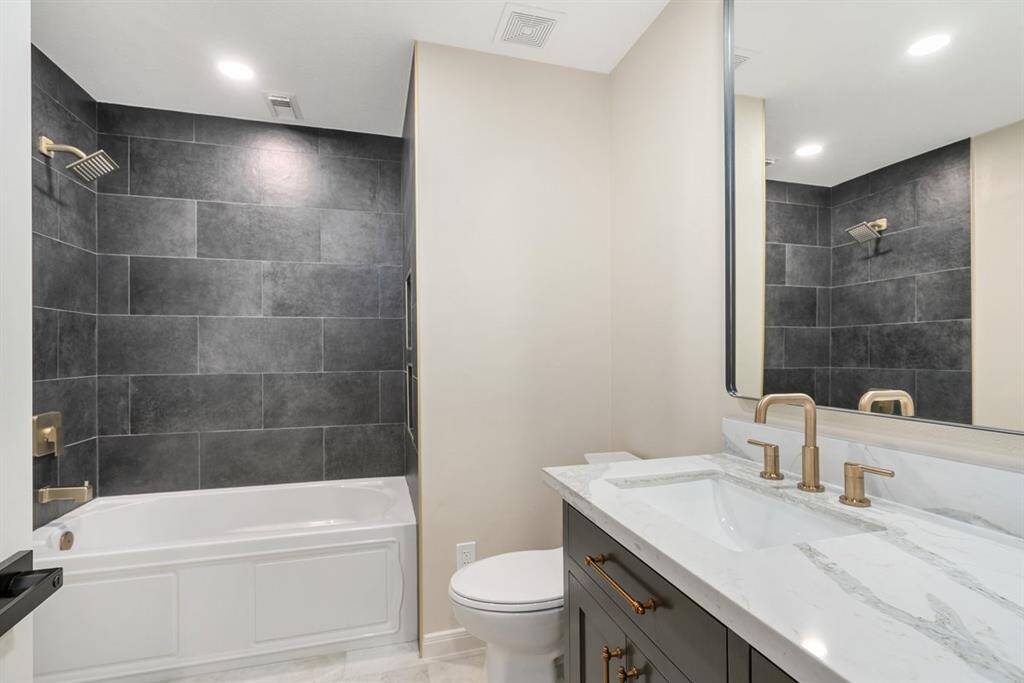 The hall bath echoes the luxurious finishes of the primary suite with tile that stretches to the ceiling, quartz counters and new vanity!