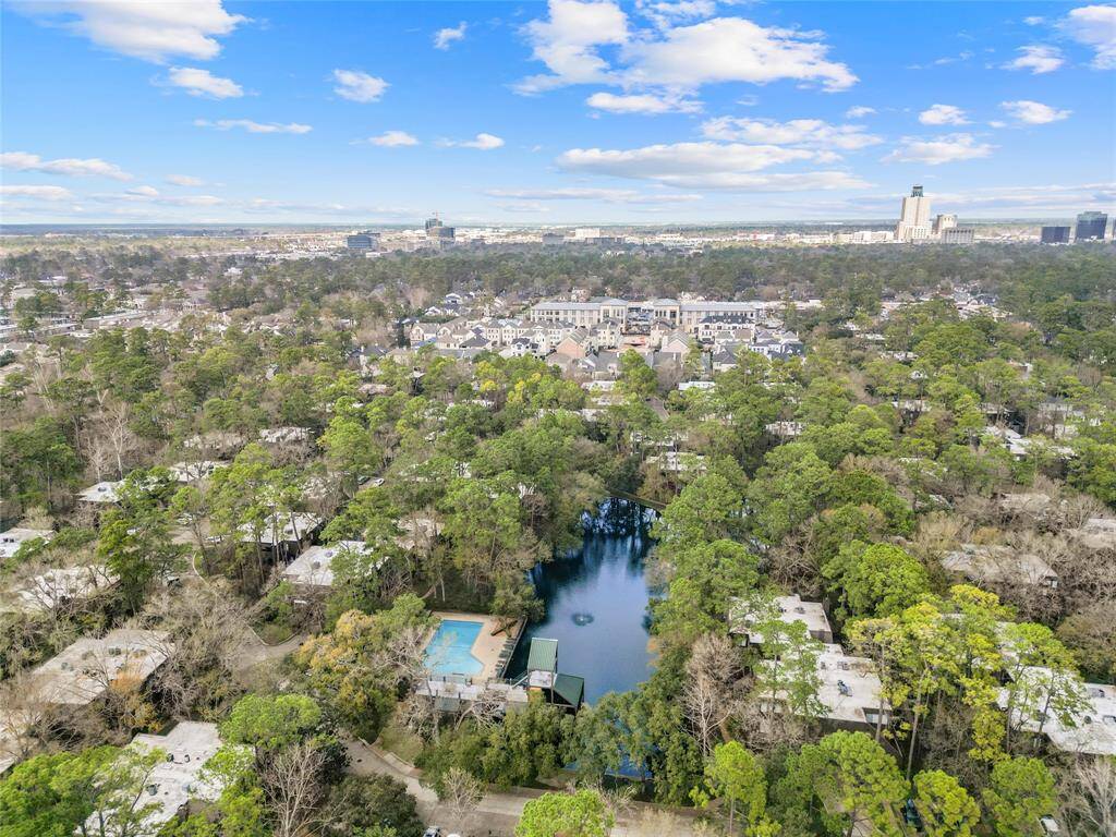 This aerial view highlights the lush, wooded community and swimming pool. Surrounded by dense trees for privacy, it offers a serene setting with convenient access to the city.