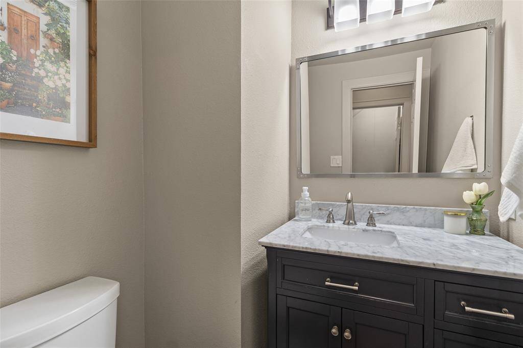 This half bathroom conveniently off of the living room features a stylish vanity with a marble countertop and modern fixtures.