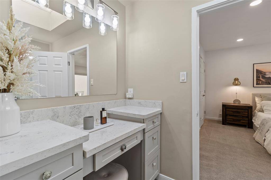 This photo showcases a bright vanity area with a large mirror, elegant lighting, and ample counter space for convenience.