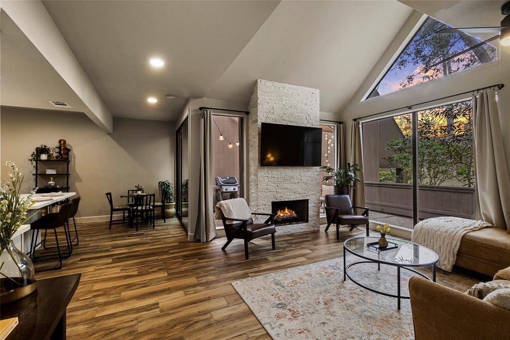 This inviting living room boasts high ceilings and expansive windows that fill the space with natural light. Overlooking a serene outdoor setting, it offers a warm and open atmosphere perfect for relaxation.