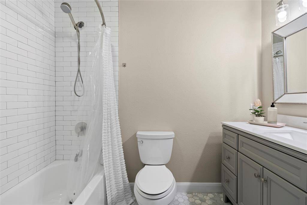A shot of your guest bathroom featuring on-trend tiling, a large vanity and thoughtful touches such as the framed mirror and upgraded vanity lights.