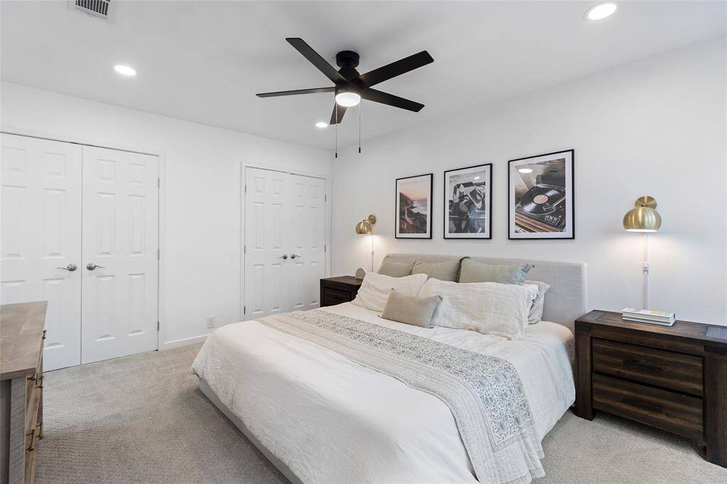 The primary bedroom features a modern design with dueling closets and an upgraded ensuite. It also has a ceiling fan and ample natural light from a large window, creating a bright and inviting space.