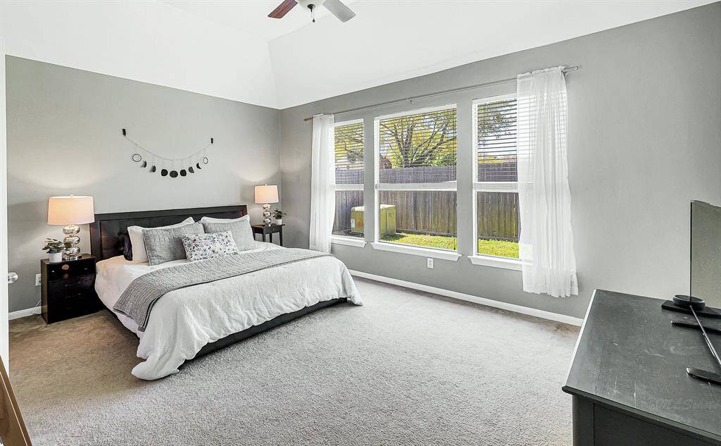 Welcome to your serene primary suite, featuring 11-foot ceilings and soothing gray paint. Dual closets offer ample storage, while three bright windows fill the room with natural light.