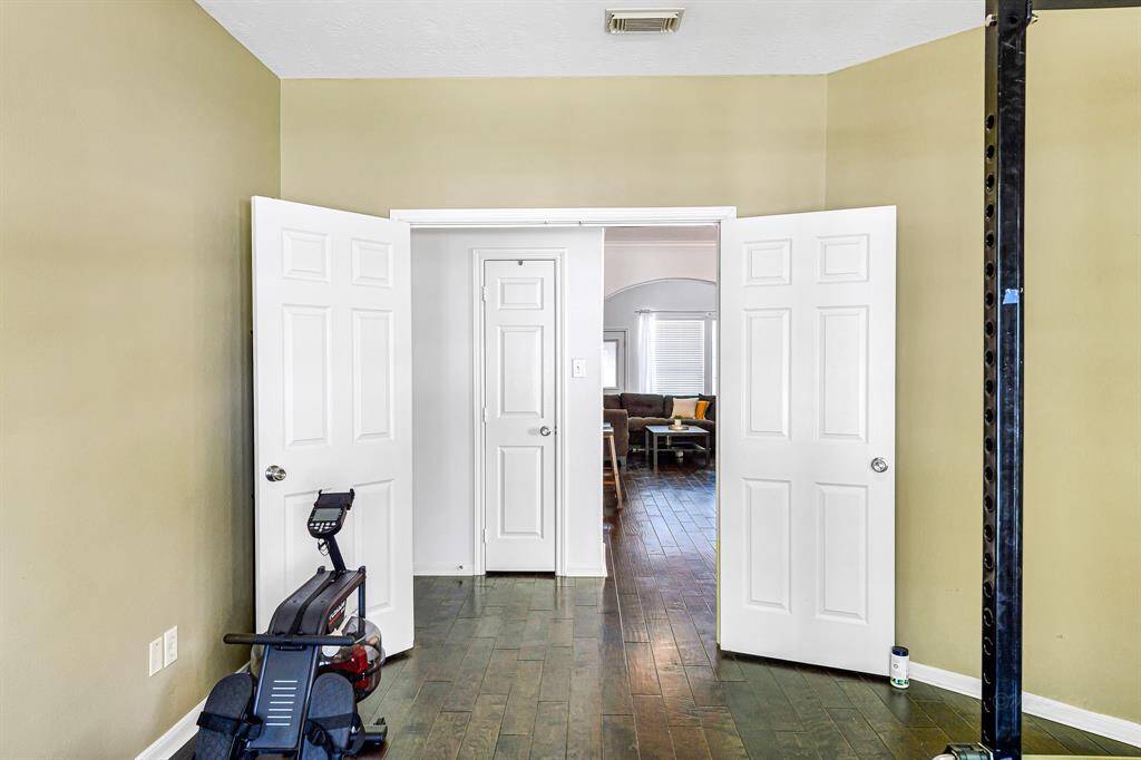This versatile space offers plenty of room for office furniture, oryou can transform it into a flex space, playroom, or workout room, as seen in the photo. Acomplementary drywall arch frames the doorway, addingarchitectural charm. Convenient storage is located just outsidethe study, and a brushed nickel ceiling fan ensures the room remains cool and comfortable.