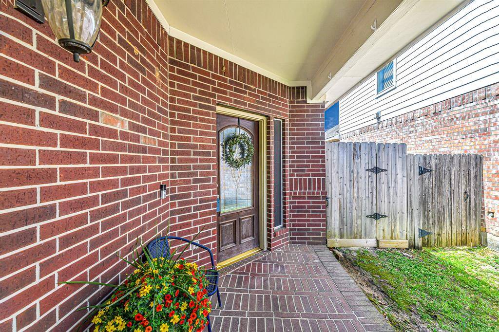 Follow the beautifullylandscaped pathway to awelcoming front porch, featuring classic brick flooring and a charming coach light.