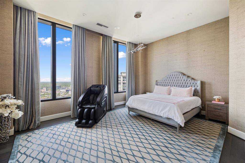 The primary bedroom is large in size, with grasscloth wallpaper and large windows with automatic black-out drapes.