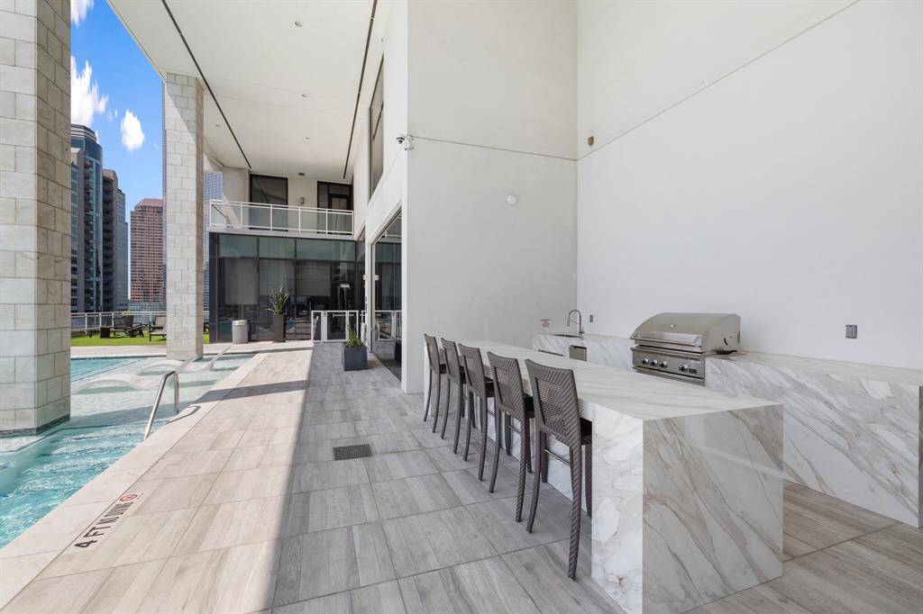 The outdoor kitchen is equipped with a grill for residents to enjoy poolside.