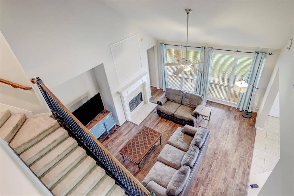 A STUNNING VIEW OF THELIVING ROOM FROM THESECOND FLOOR,SHOWCASING VAULTEDCEILINGS, WOOD FLOORING,AND ABUNDANT NATURALLIGHT.