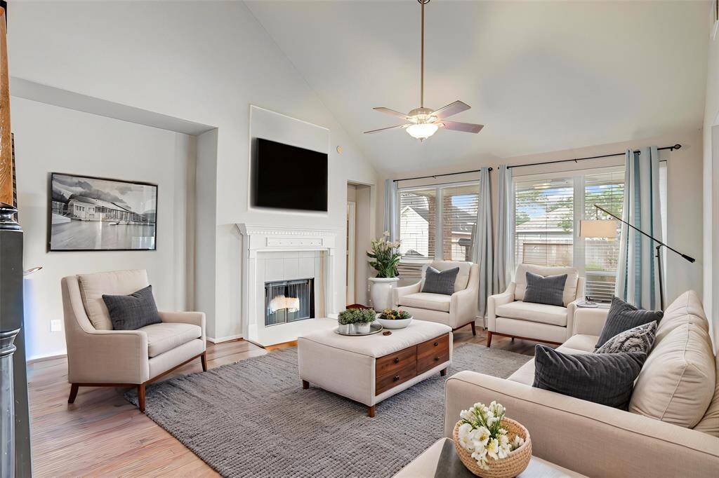 SPACIOUS LIVING AREA WITHWOOD FLOORING, A WOODBURNING FIREPLACE, ANDLARGE WINDOWSOVERLOOKING THEBACKYARD. **This room has been virtually staged.
