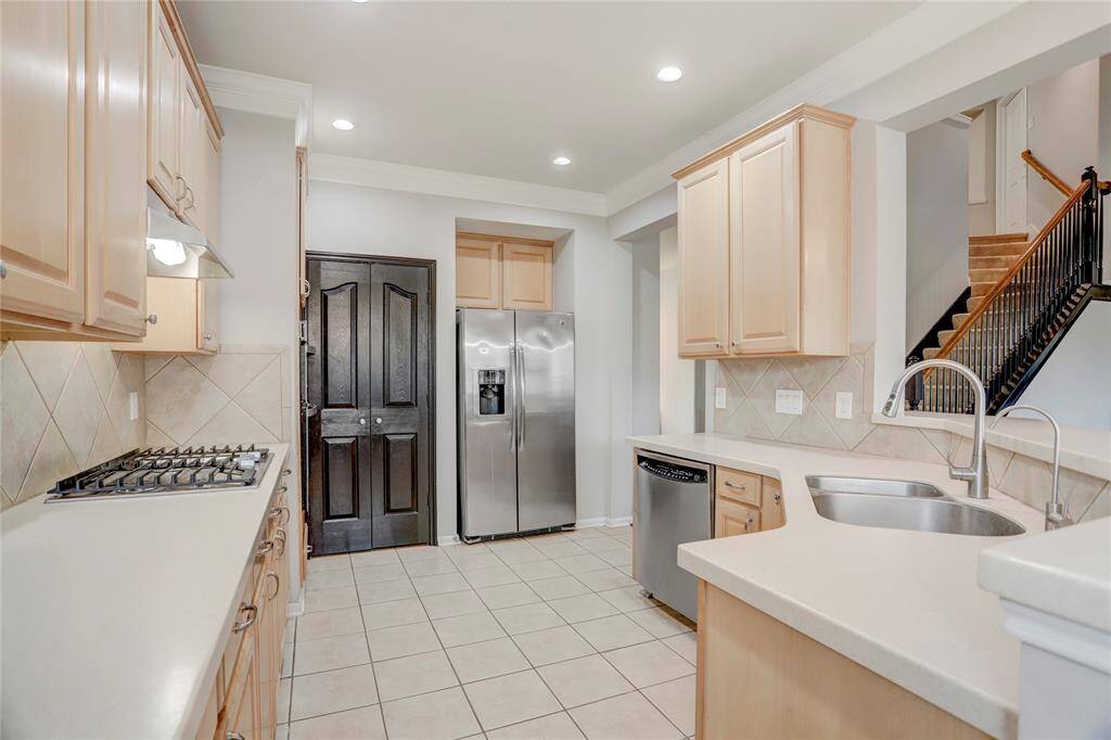 BRIGHT AND FUNCTIONALKITCHEN FEATURING LIGHTCABINETRY, STAINLESSSTEEL APPLIANCES, AND APANTRY WITH A STRIKINGDARK DOOR