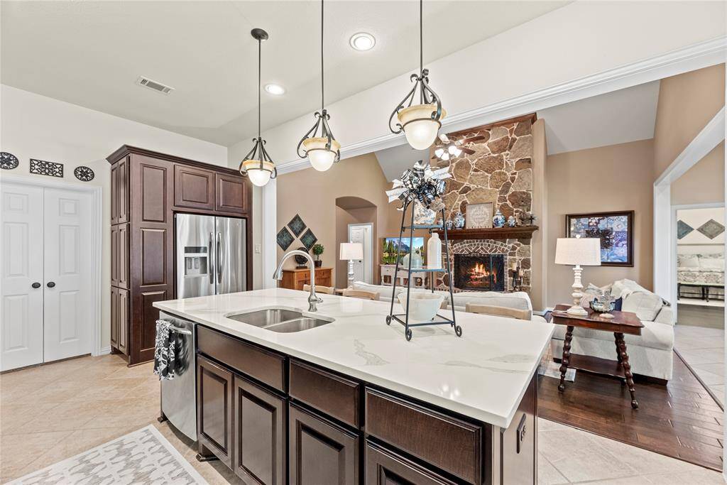 The sprawling island with statement pendant lights and breakfast bar seating serves as a versatile centerpiece, providing additional workspace, storage, and seating for casual dining or entertaining.