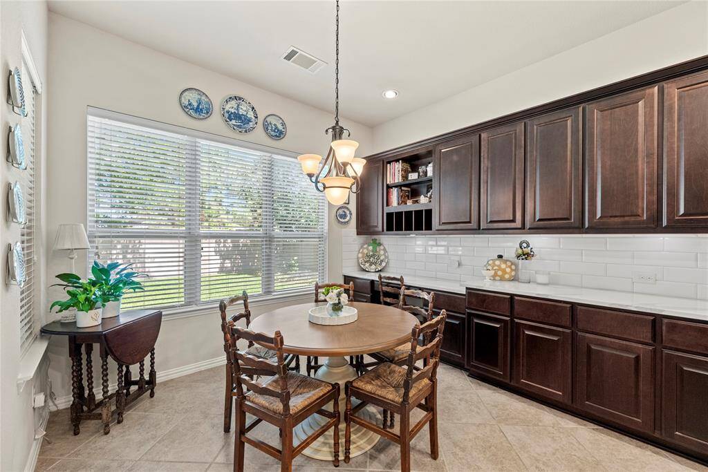 The breakfast room is ideal for a full-sized table and features easy care tile floors, large bright windows, overhead chandelier, and an additional desk area with coordinating counter and cabinet space.