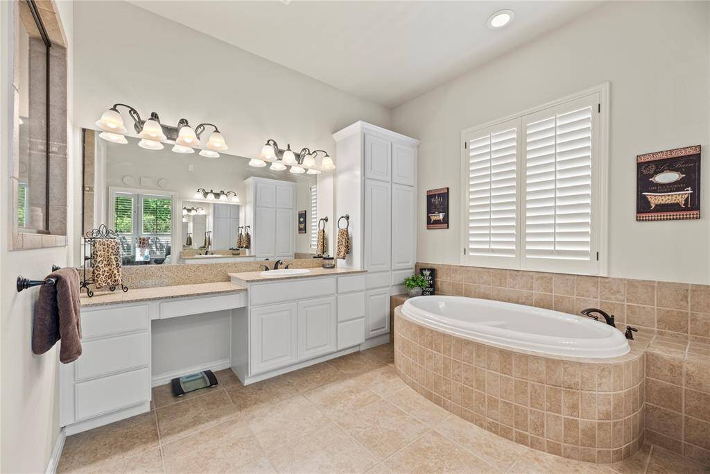 The primary bath features dual vanities, providing ample personal space along with an abundance of custom cabinetry for seamless organization. The freestanding soaking tub offers a serene retreat, inviting you to unwind and indulge in pure relaxation.