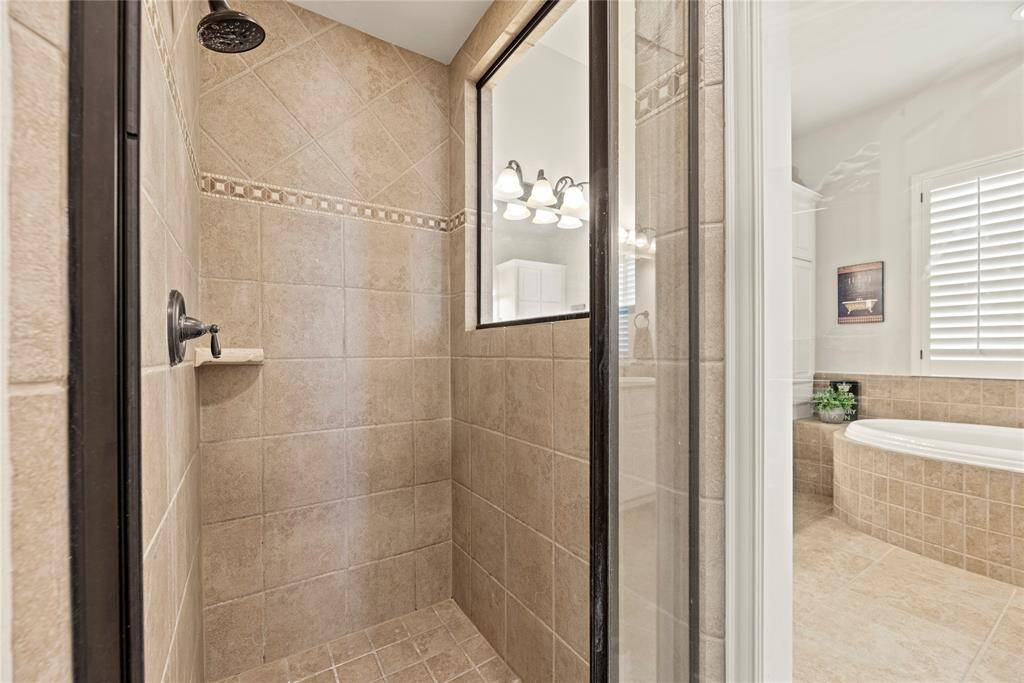 The expansive walk-in shower, adorned with stunning tile work and a sleek glass front, offers a luxurious escape for a quick rinse or a refreshing retreat.