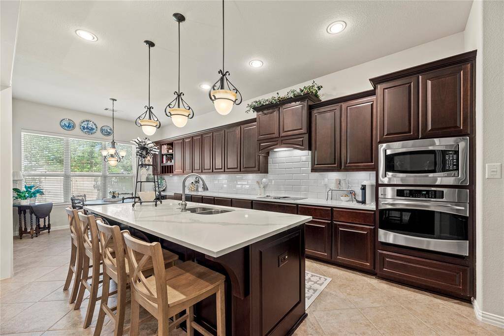 Your chef inspired kitchen awaits! Features include quartz countertops paired with a coordinating tile backsplash, stainless steel appliances, rich cabinets, under cabinet lighting, recessed lighting, and a sprawling island with breakfast bar seating.