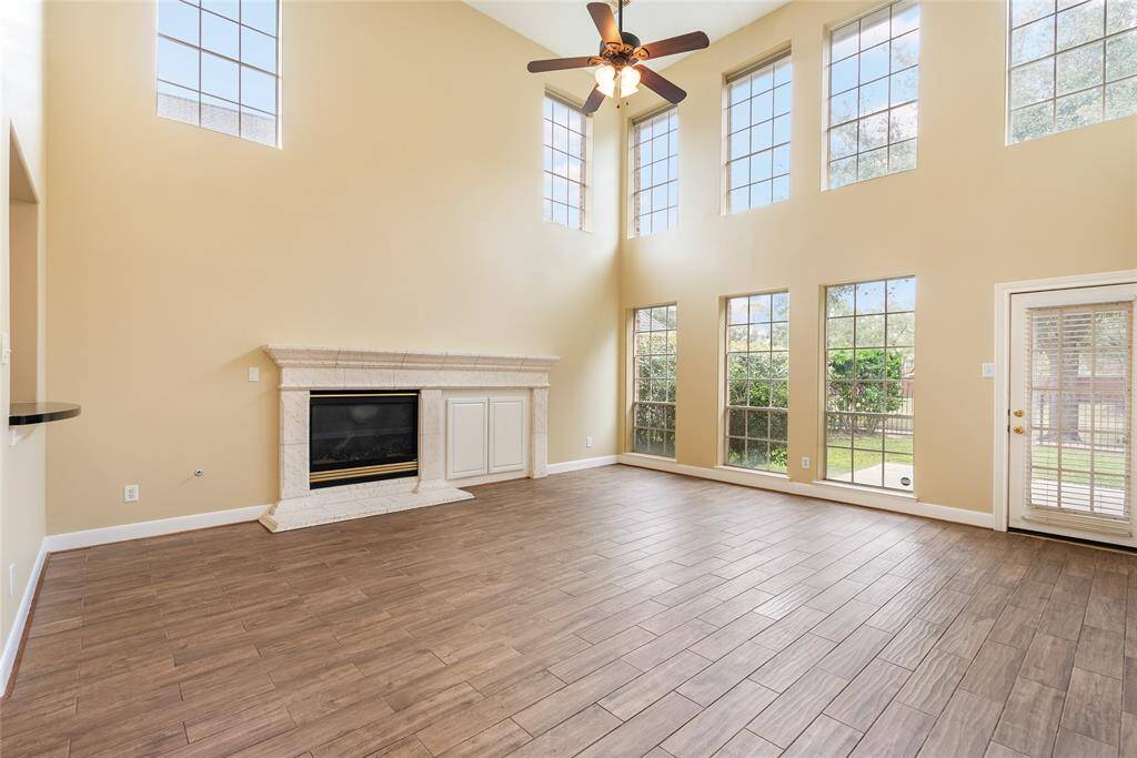 The grand two-story living room with convenient gas fireplace, extra large limestone mantle and hearth, and added storage area overlook the backyard and lake.