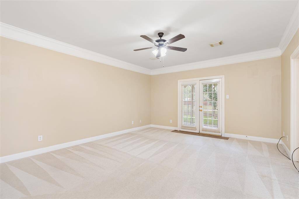 The primary bedroom has French doors that lead to the patio, which overlooks the lake and neighboring pool.