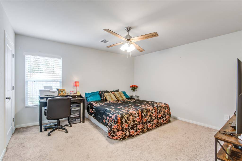 This spacious bedroom features a ceiling fan, plush carpet, and ample natural light from a large window.