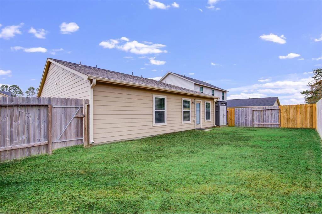 Charming backyard with a well-maintained lawn, enclosed by a wooden fence for privacy. The home's exterior features neutral siding and a sloped roof, offering a cozy and inviting space.