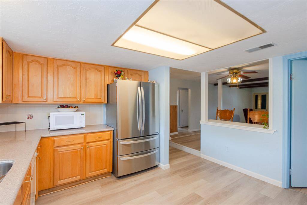 Large living room with new floors, exposed beams, and a gas fire place is a very inviting space for everyone