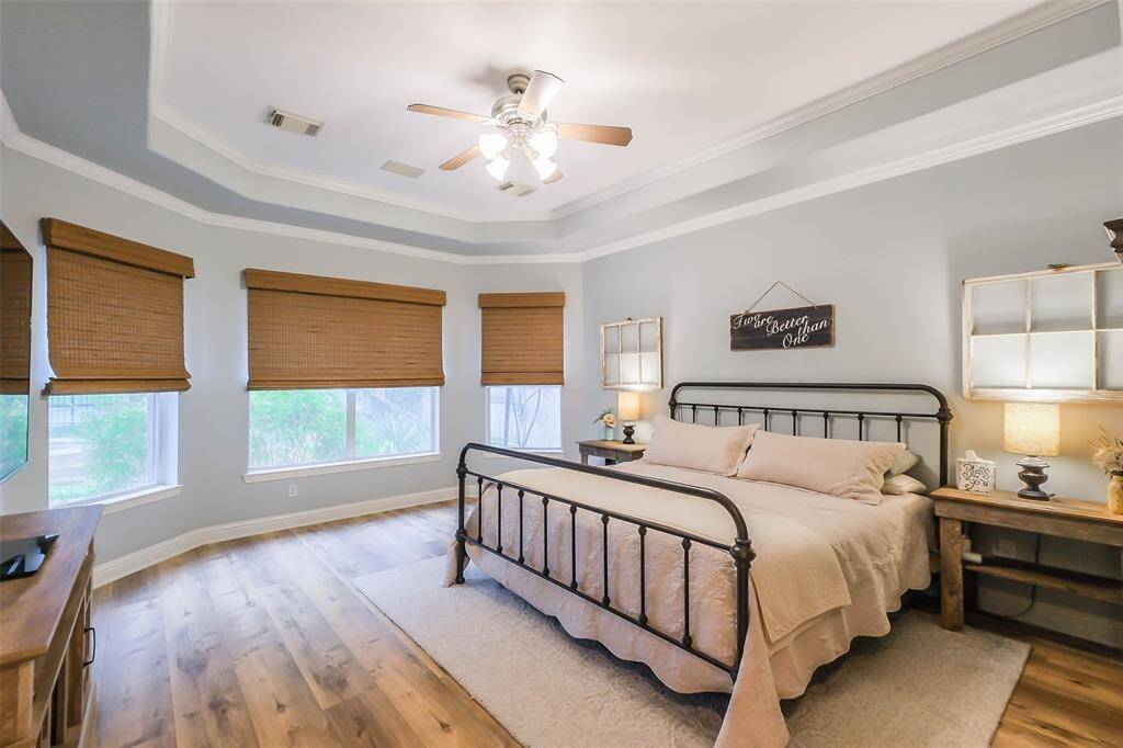 Primary bedroom downstairs with tray ceilings, crown molding and a beautiful view of your backyard oasis.