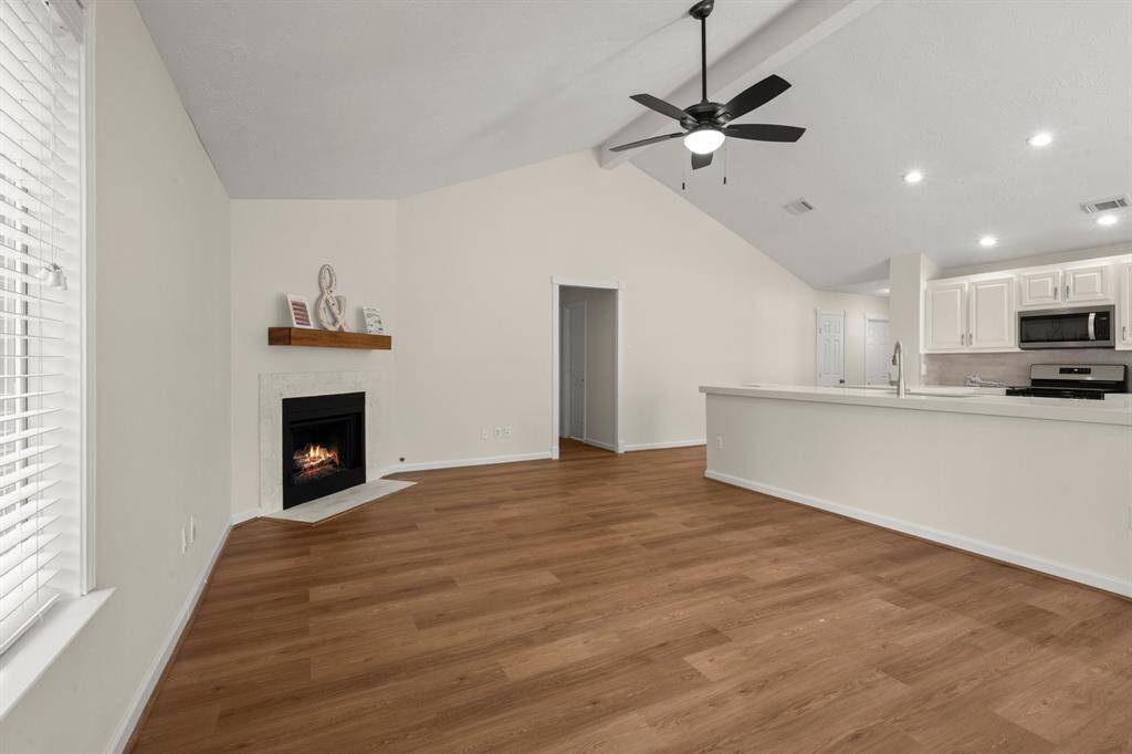 Fresh paint throughout, modern vinyl plank flooring, updated ceiling fan and lighting, and a beautifully retiled fireplace creating a warm focal point.