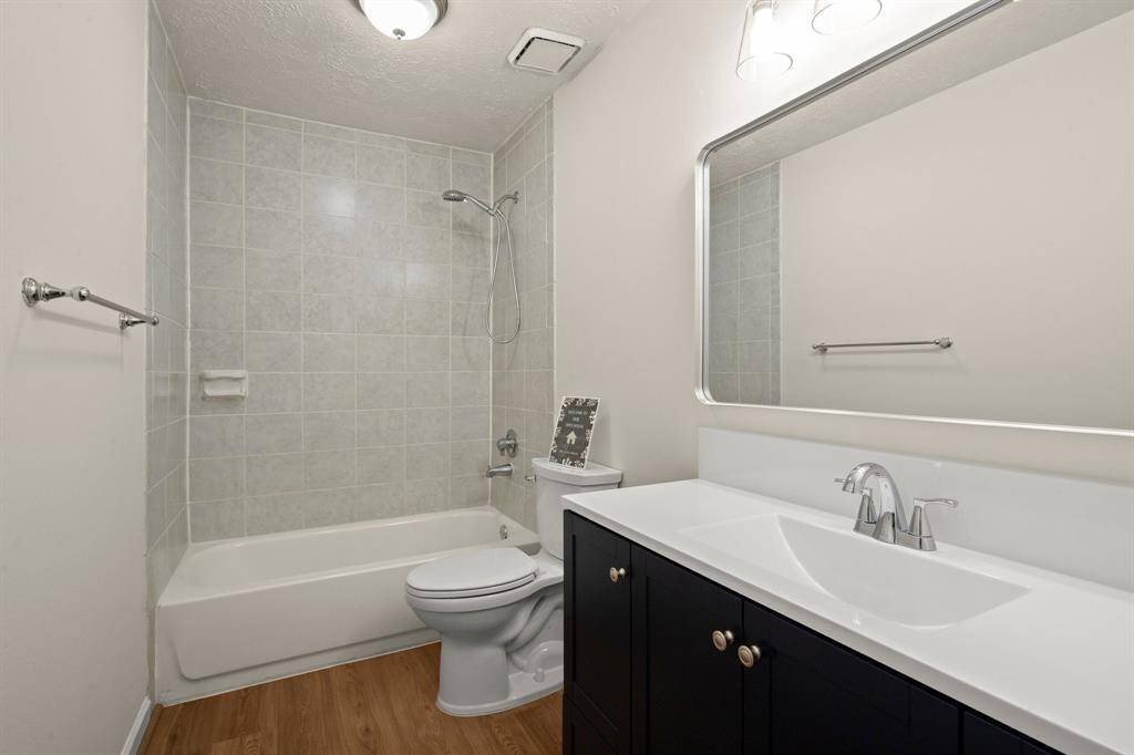 The remodeled guest bath is move-in ready with a new vanity, modern toilet, upgraded lighting, stylish flooring, and a fresh, clean aesthetic.