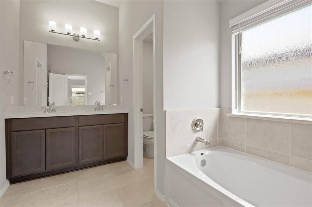 The primary bathroom offers a spa-like retreat, boasting a separate shower and garden tub, double vanities, tile flooring, and a generous walk-in closet.