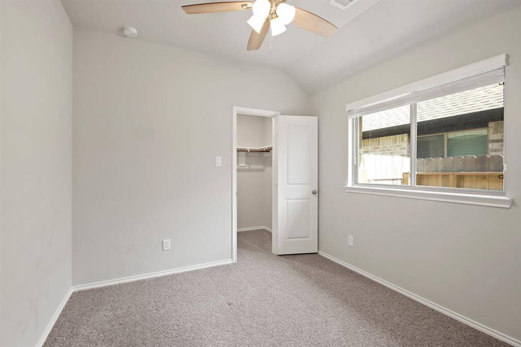 The three secondary bedrooms feature neutral paint, soft carpeting, and ceiling fans for added comfort.