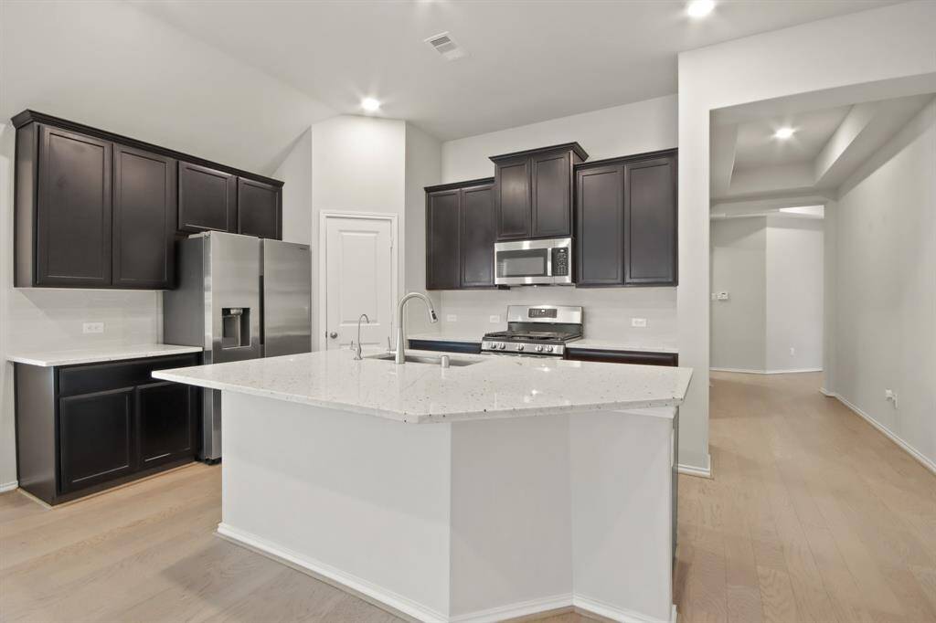 A spacious island with granite countertops, deep stainless sink, gas range & walk-in pantry!