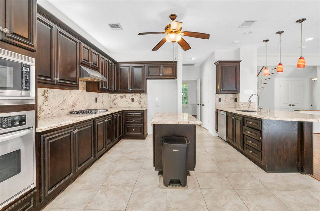Kitchen with new tile (September 2024), GE gas stove with 5 burners, one of which is a double burner.  Sink area has an instant hot water dispenser.